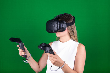 woman wearing virtual reality headset with handheld  controllers over green screen