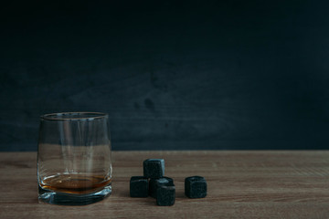 Stones for cooling whiskey and glases tumbler on dark wooden background