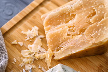 Delicious cheese on wooden cutting board, closeup
