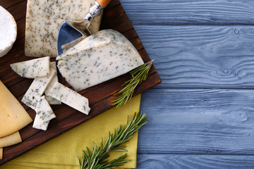 Sliced cheese with herbs on wooden board