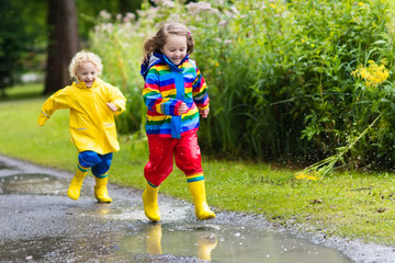 Kids play in rain and puddle in autumn