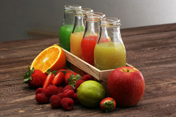 several bottles with fruit and berry juices smoothies and milkshakes , vintage wooden background, selective focus