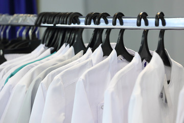 Medical uniform on a hangers in a shop - obrazy, fototapety, plakaty