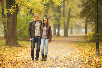 Young couple walking in autumn park and smiling