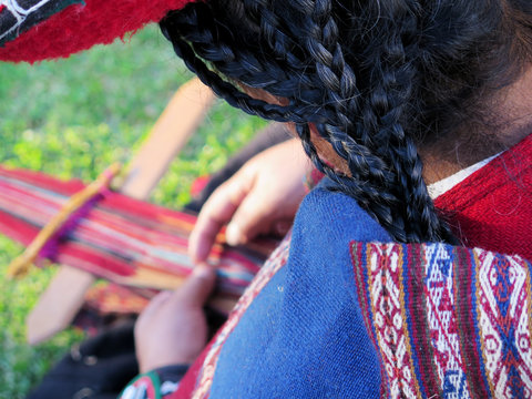 Close up of Peruvian lady in authentic dress spinning yarn by hand