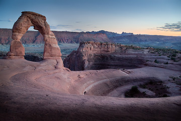 panorama delicate arch sunset car tail lights in the distance