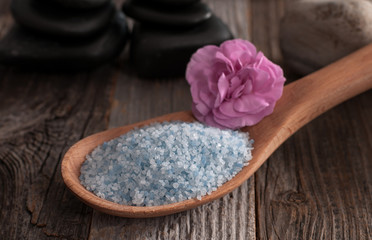 Wooden spoon full of sea salt on wooden background