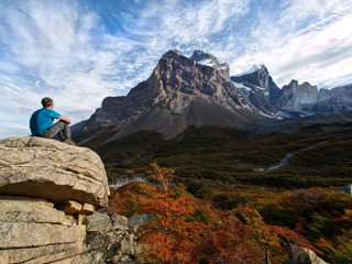 Fototapeta premium Young man sitting and enjoying scenic view at a high mountain