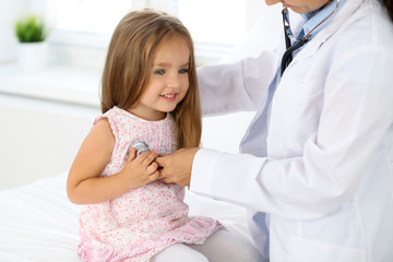 Fototapeta premium Doctor examining a little girl by stethoscope