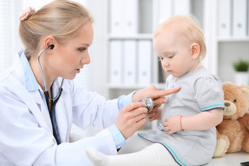 Pediatrician is taking care of baby in hospital. Little girl is being examine by doctor with stethoscope. Health care, insurance and help concept.