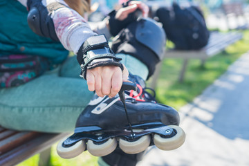 Fototapeta na wymiar Roller girl unscrewing wheels on freeskate roller Skates with Allen key or Hex key tool. Maintenance of professional skates