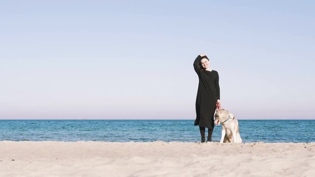 Young female standing with siberian husky dog with beach background
