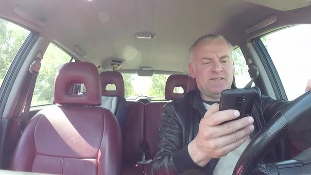 People, travel and communication technology. Man with mobile telephone, driver with cell phone, driving car on the street, using smartphone for text messaging and internet. Danger and risk on the road
