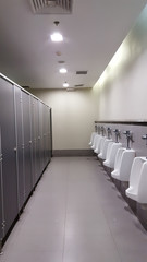 line of white automatic porcelain urinals in public toilets