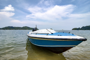Pangkor Island located at Malaysia.Blue fiber boat moored over cloudy blue sky background