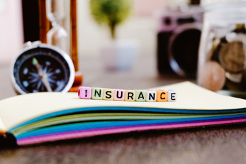 conceptual image with INSURANCE word block on note pad over soft focus bakground