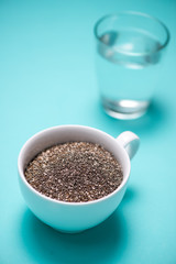 Fototapeta na wymiar Glass of water and healthy chia seeds in a cup. Text space.