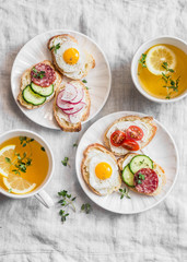 Delicious Breakfast - mini sandwiches with cream cheese, vegetables, quail eggs, salami and green tea with lemon and thyme.s, radish, thyme, lemon zest, fried quail eggs 