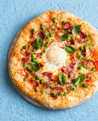 Egg, bacon pizza on a blue background, top view. Breakfast pizza