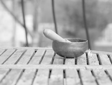 Tibetan singing bowl on a wooden table. black and white photo.
