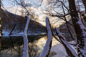 Scenery of wild river with sunset sky reflection in the mountains, in winter