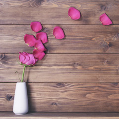 Wooden background witn pink rose on vase