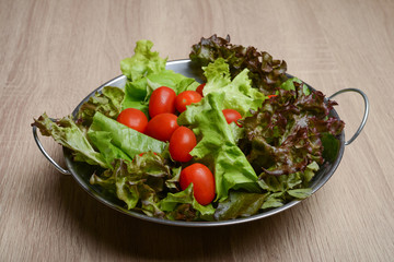 Fresh salad with vegetables and greens on wooden table. Healthy food concept.
