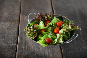 fresh vegetables salad in the bowl with rustic old wooden background.