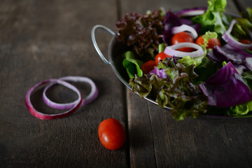 fresh vegetables salad in the bowl with rustic old wooden background.