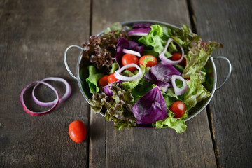 fresh vegetables salad in the bowl with rustic old wooden background.