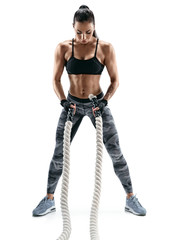 A strong woman is preparing to work with heavy ropes. Photo of attractive woman in sportswear isolated on white background. Strength and motivation.