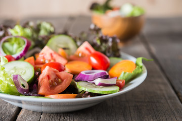 Close up of fresh vegetables salad in the bowl with rustic old wooden background. Healthy food concept.