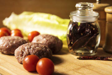 Raw cutlets lie on a board with vegetables