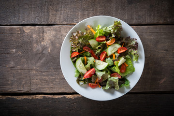 Top view of fresh vegetable salad on wooden background.