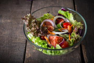 Fototapeta na wymiar Fresh vegetable salad in glass bowl on wooden background.