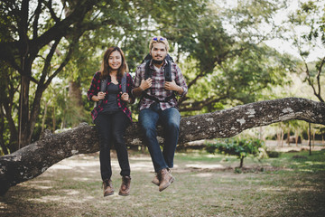 Young hikers couple take a rest sitting on branch enjoy with nature. Travel concept.