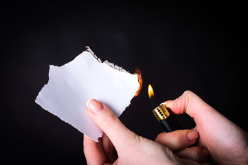Set fire to a sheet of paper on a dark background