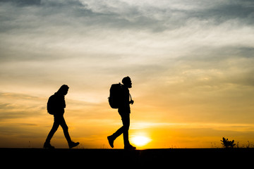 Fototapeta na wymiar Silhouettes of two hikers with backpacks enjoying sunset. Travel concept.