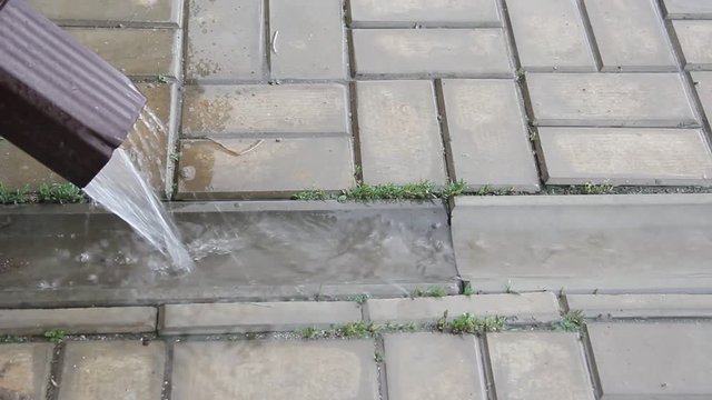 Rain water flowing from drain pipe closeup