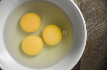 A fresh egg in a glass bowl on wooden background.