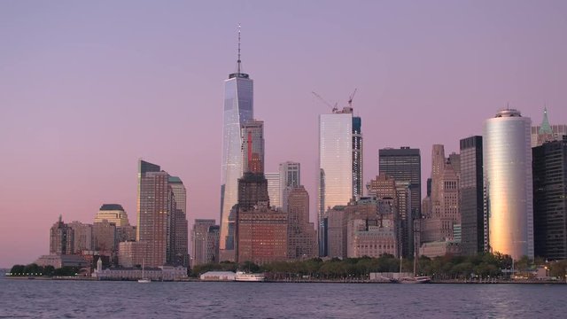 Iconic contemporary glassy skyscrapers lit up against stunning purple-pink sky of a dawn in Lower Manhattan, New York City. Modern architecture in developed metropolitan urban city at magical sunrise