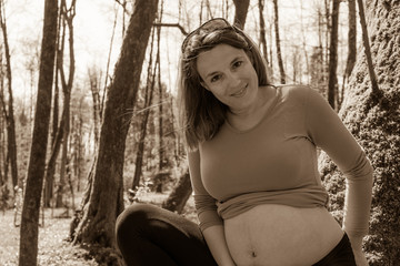 Young pregnant woman posing in park.