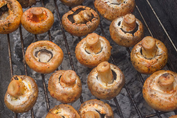 Field mushrooms cooking outdoor on smouldering carbons