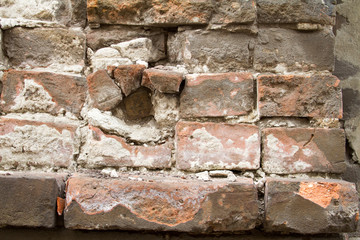 Vintage background texture of old brick masonry on ancient cement with cracks with traces of old paint.