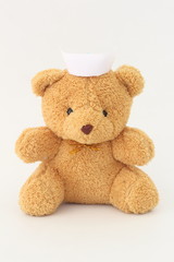 Teddy bear wearing a nurse hat on a white background.