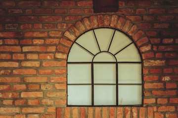 Big rounded window on red brick wall