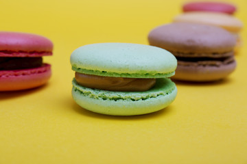 Tasty different colored macarons on yellow background