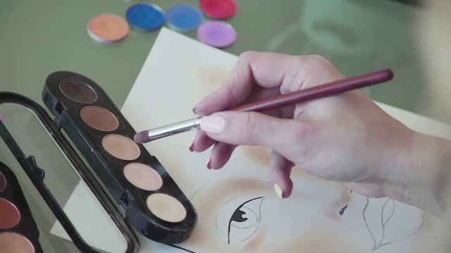 A woman make-up artist learns to apply make-up using the face map. Make up artist comes up with makeup using a face chart. Beauty and fashion industry: Facechart. Face chart of cosmetic brand