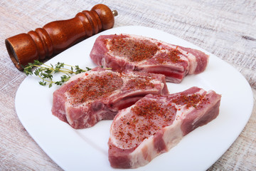 Raw pork chops and spice grinder on cutting board. Ready for cooking.