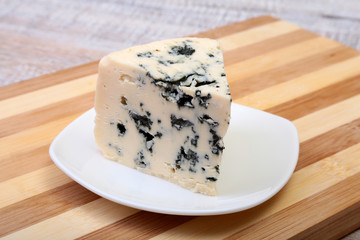 Plate with Tasty blue cheese on wooden table